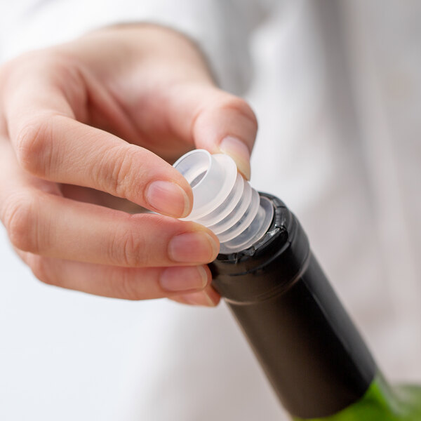 A hand using a Franmara Slo-Vino wine pourer to open a bottle of wine.