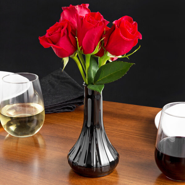 A black Cambro Bud Vase with red roses on a table.
