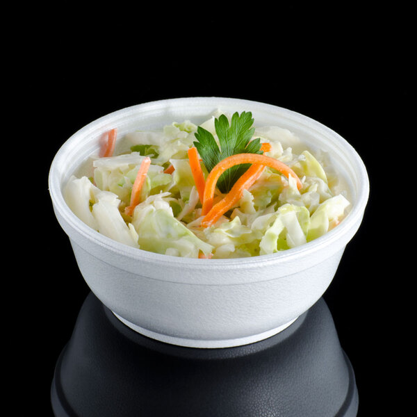 A Dart insulated foam bowl filled with salad, carrots, and greens.
