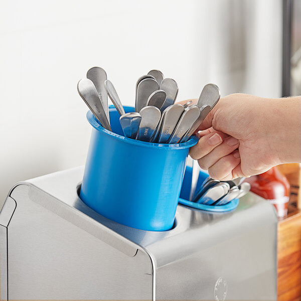 A blue Steril-Sil flatware cylinder filled with silverware on a counter.