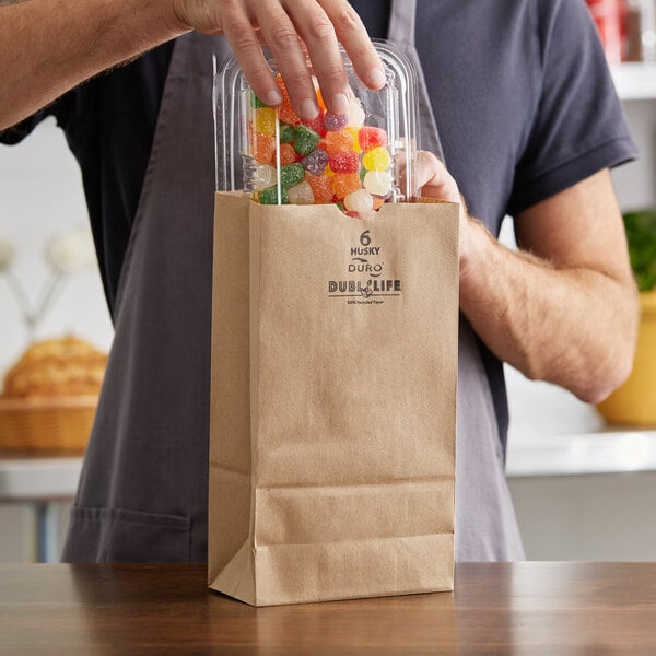 A person holding a Duro paper bag full of gummy candies.