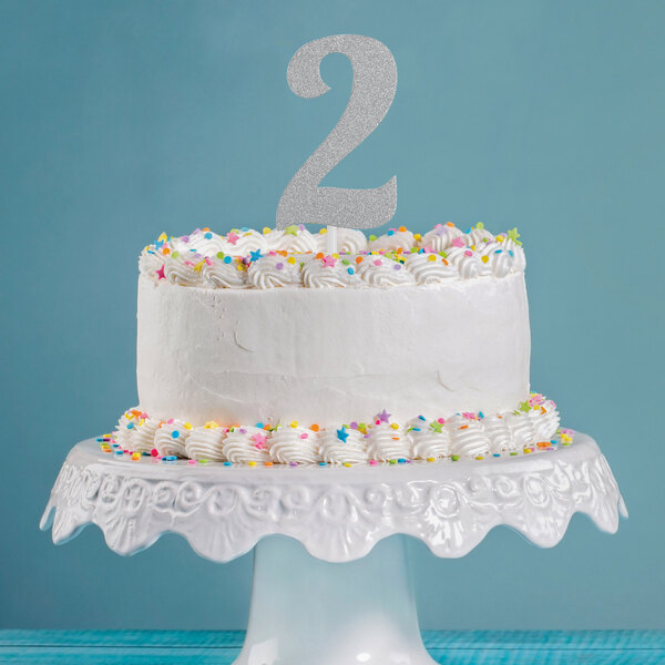 A white cake with a silver glitter number two on top.