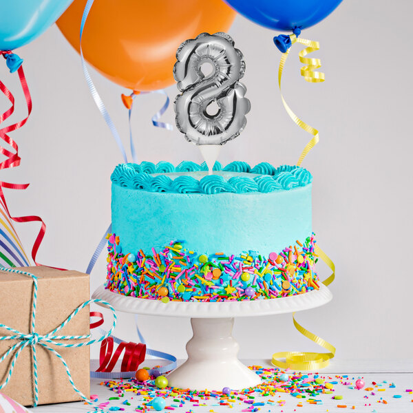 A white birthday cake with a silver "8" balloon cake topper.