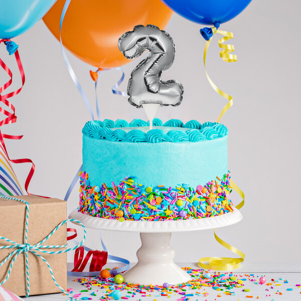 A white birthday cake with a silver "2" balloon on top.