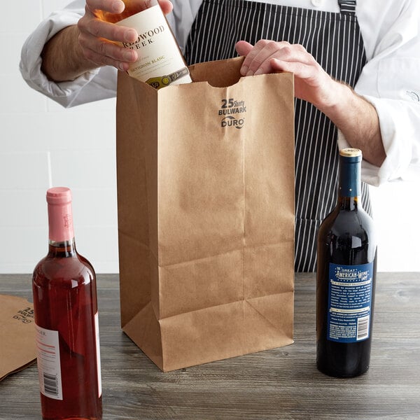 A person holding a bottle of wine in a brown Duro paper bag.
