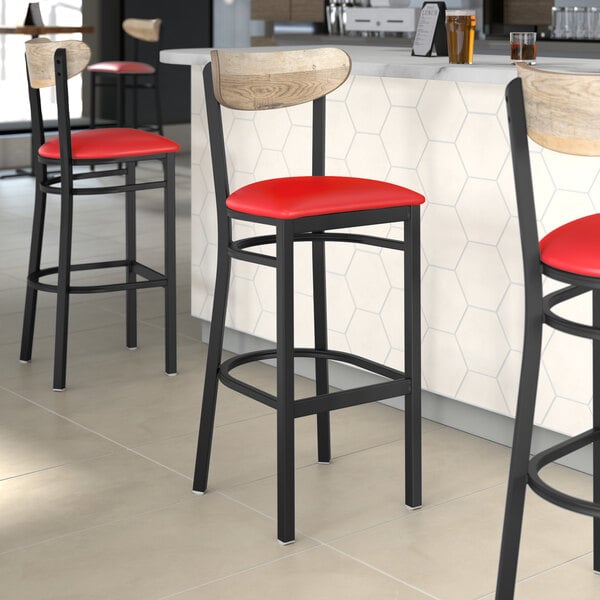 Three Lancaster Table & Seating black bar stools with red vinyl seats and driftwood backs at a restaurant bar.