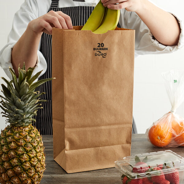 A woman putting bananas in a Duro Bulwark brown paper bag.