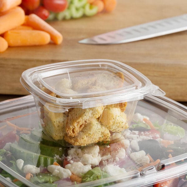A Dart ClearPac plastic container with food in it next to a knife.