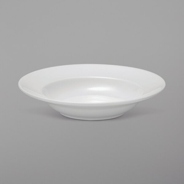A Oneida Royale bright white porcelain wide rim pasta bowl on a gray surface.
