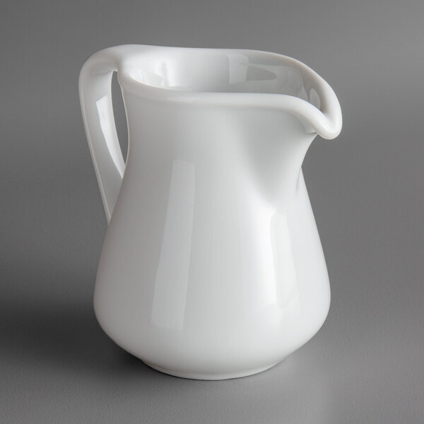 A Oneida Royale bright white porcelain creamer on a gray surface.