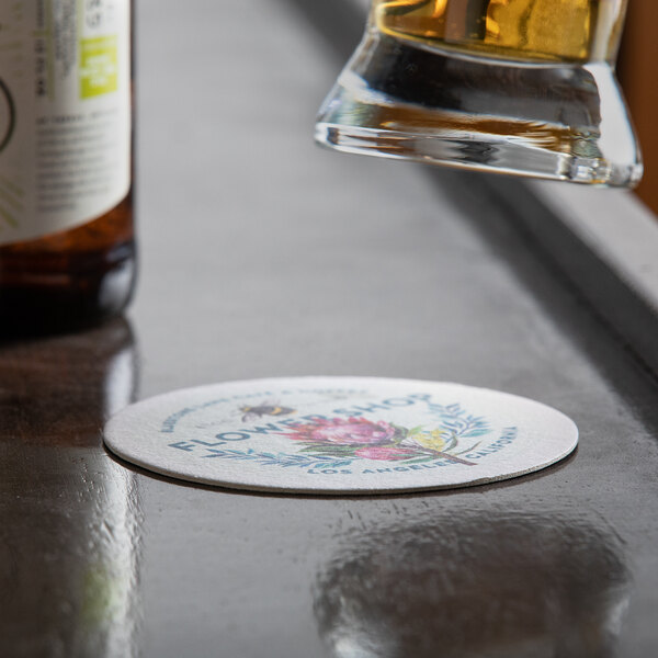 A glass of beer on a 4" white customizable paper coaster.