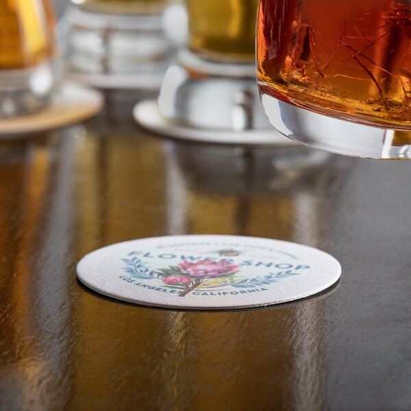 A customizable paper coaster with a drink on it on a table in a brewery tasting room.