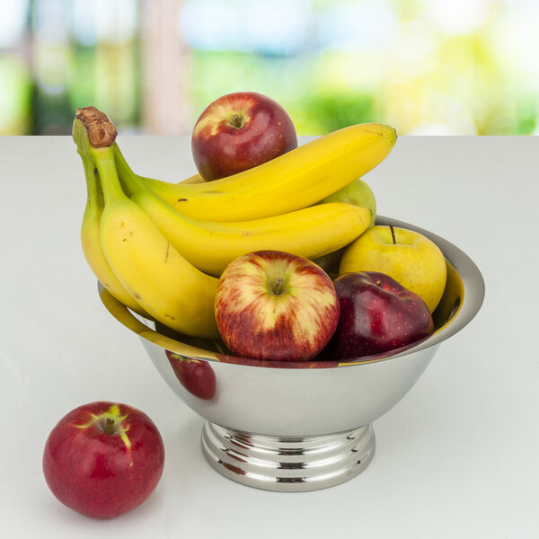 A Tabletop Classics by Walco stainless steel bowl filled with apples and bananas on a table.