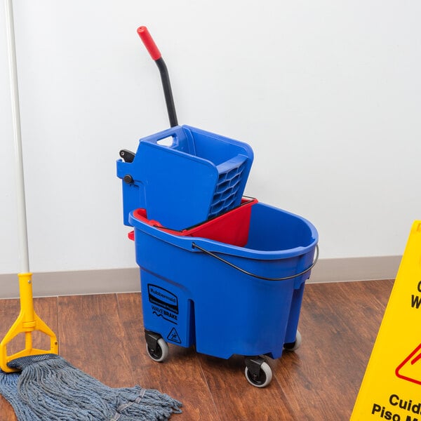 A Rubbermaid blue mop bucket with red wringer and dirty water bucket on the floor.