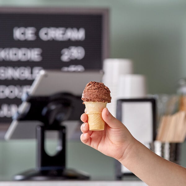 A hand holding a JOY Kids flat bottom cake ice cream cone.