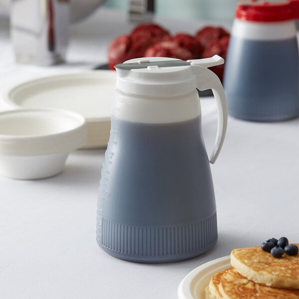 A Vollrath Dripcut polyethylene server with white top on a table with pancakes and syrup.