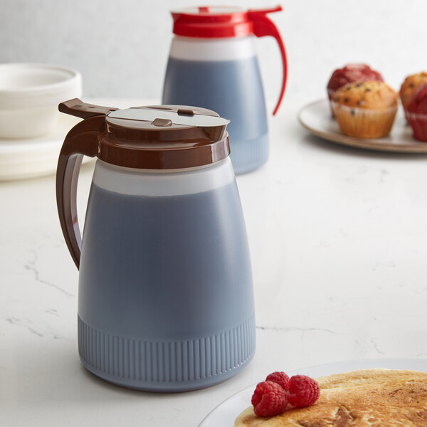 A Vollrath white polyethylene server with a brown lid on a pitcher of liquid.
