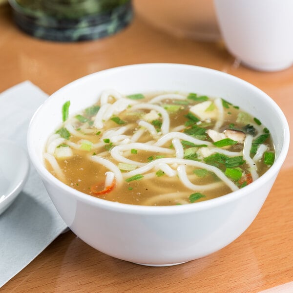 A white melamine bowl filled with soup, noodles, and vegetables.