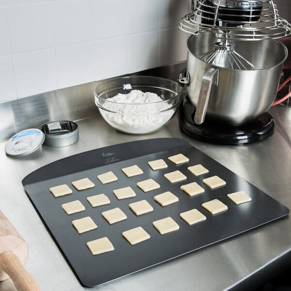 A Wilton rimless steel cookie sheet on a counter with cookies on it.