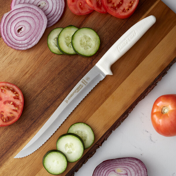 A Dexter-Russell Sani-Safe scalloped utility knife cutting tomatoes, cucumbers, and onions on a cutting board.