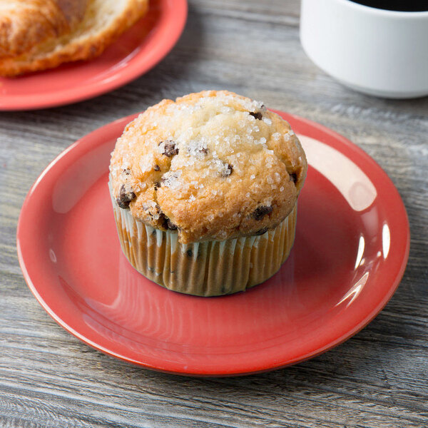 A muffin on a GET Rio Orange melamine plate with sugar on top, on a table in a breakfast diner.