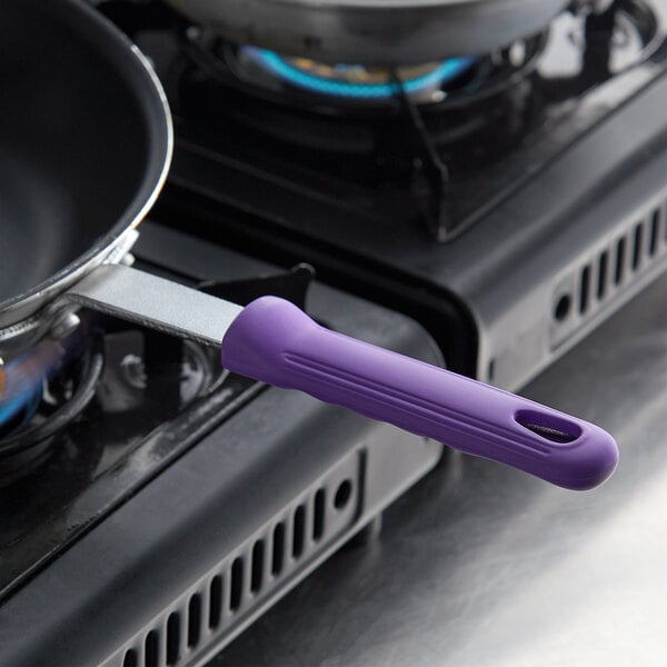 A purple Vollrath pan handle sleeve on a frying pan on a stove.