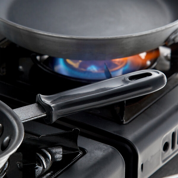 A Vollrath black silicone handle sleeve on a pan on a stove.