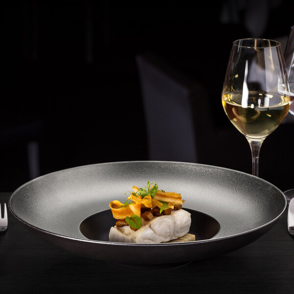A RAK Porcelain silver and black gourmet deep plate with food on a table.