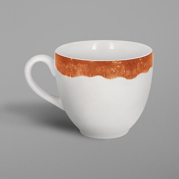 A white porcelain coffee cup with a brown rim and orange paint on it.
