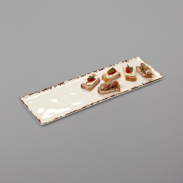 A rectangular white melamine platter with small sandwiches on it.