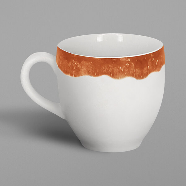 A white porcelain espresso cup with a brown rim and orange paint on the inside and handle.