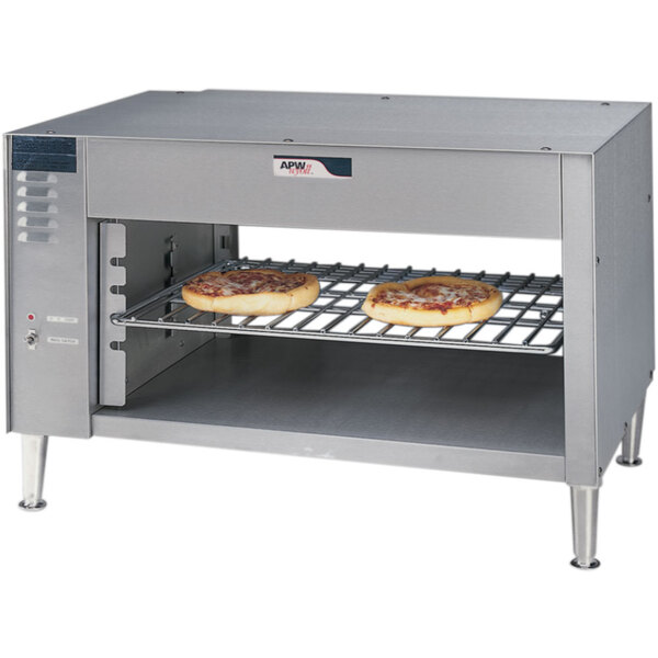 An APW Wyott cheese melter with two pizzas on a rack.