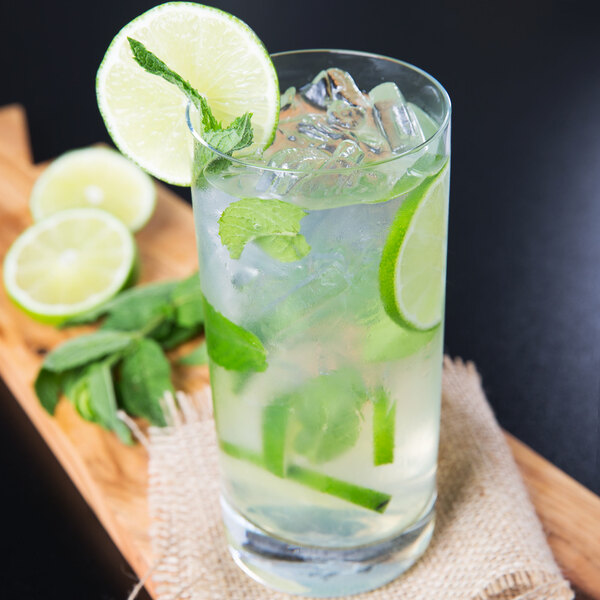 A Stolzle highball glass filled with liquid, ice, and lime slices.