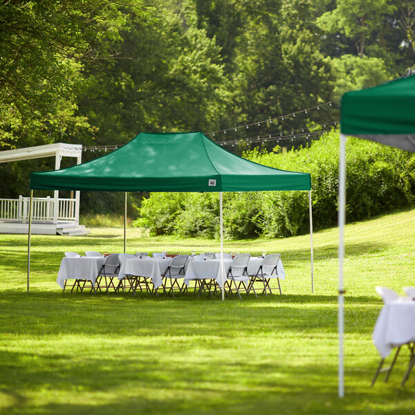A Backyard Pro green canopy set up with tables and chairs on a grassy area.