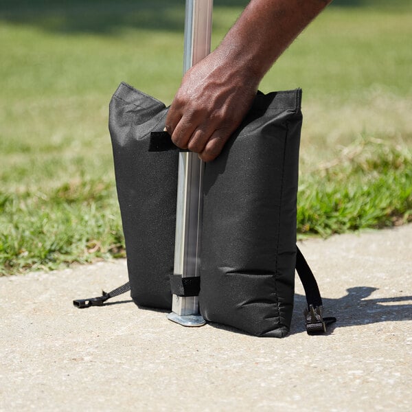 A person holding a black Backyard Pro weight bag.