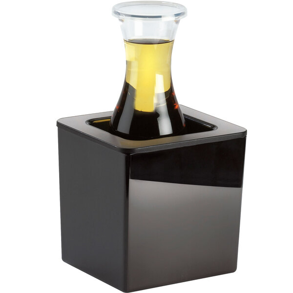 A black square container with a clear pan inside holding a bottle of liquid.