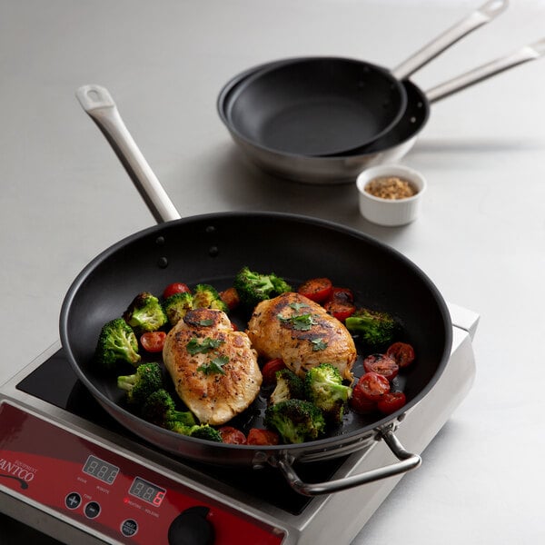 A Vigor stainless steel non-stick frying pan with chicken and vegetables cooking in it.