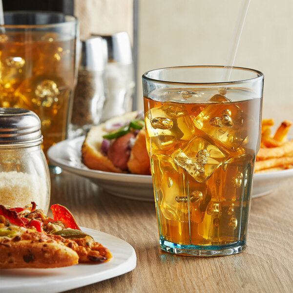 A plate of food and a Bahama jade plastic tumbler filled with ice tea on a table.