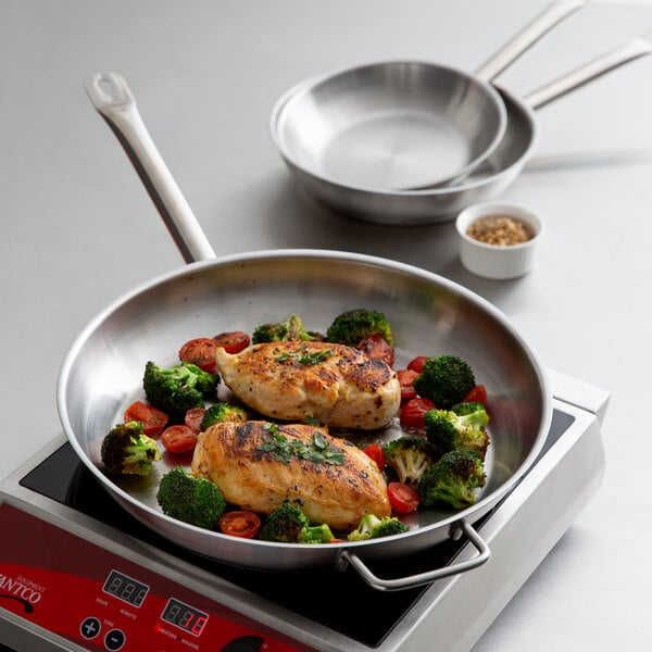 A Vigor stainless steel frying pan with chicken and broccoli cooking in it.