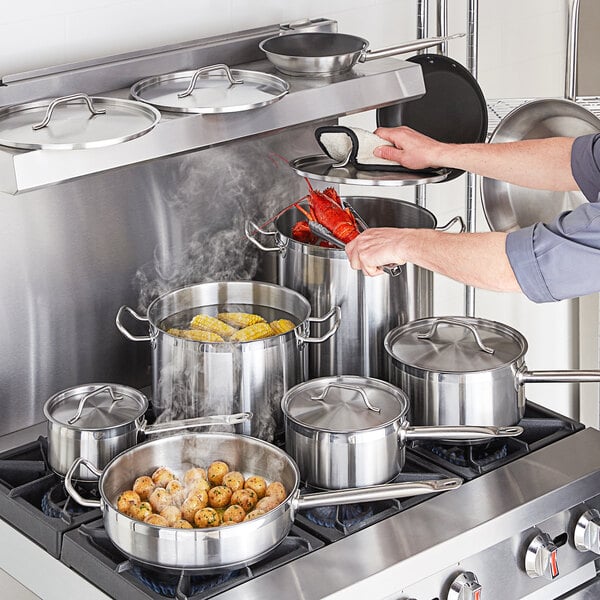 A man cooking food with Vigor stainless steel pots and pans on a stove.