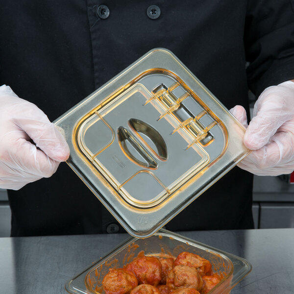 A gloved hand using a Cambro H-Pan FlipLid on a plastic food container.