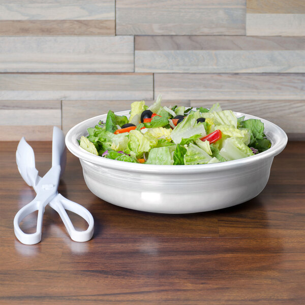 A Fiesta white china bowl filled with salad on a table.