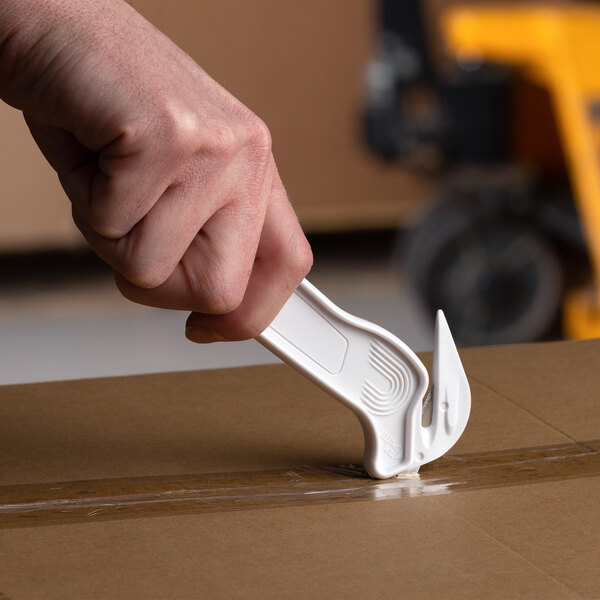 A hand using a white Pacific Handy Cutter to cut a box.