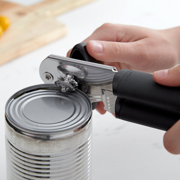 A person using an OXO Soft-Handled Can Opener to open a can.