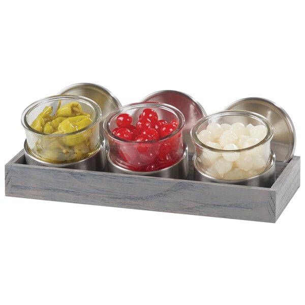 A Cal-Mil Ashwood display with three glass jars filled with different colored foods.
