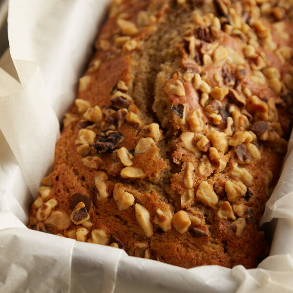 A loaf of banana bread with raw walnut pieces on top.