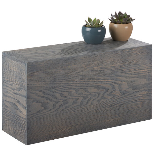 A Cal-Mil gray oak wood rectangular riser with two potted plants on it.