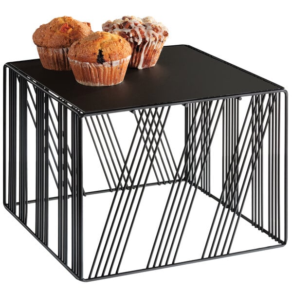 A black square metal riser with muffins on it.