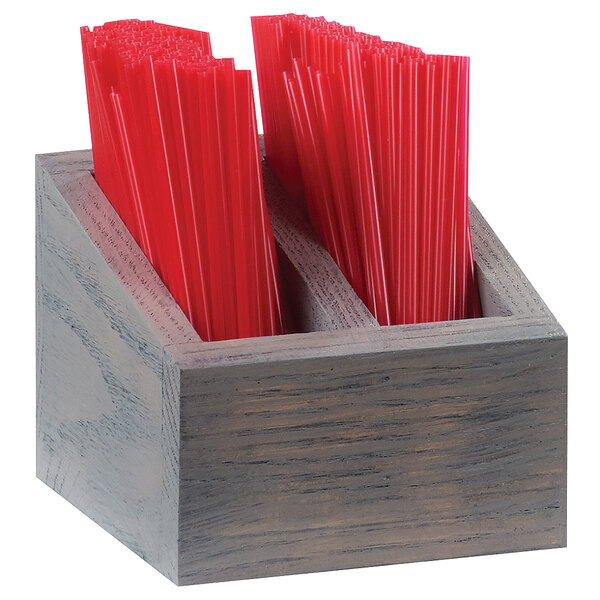 A wooden container with straws in it on a table.