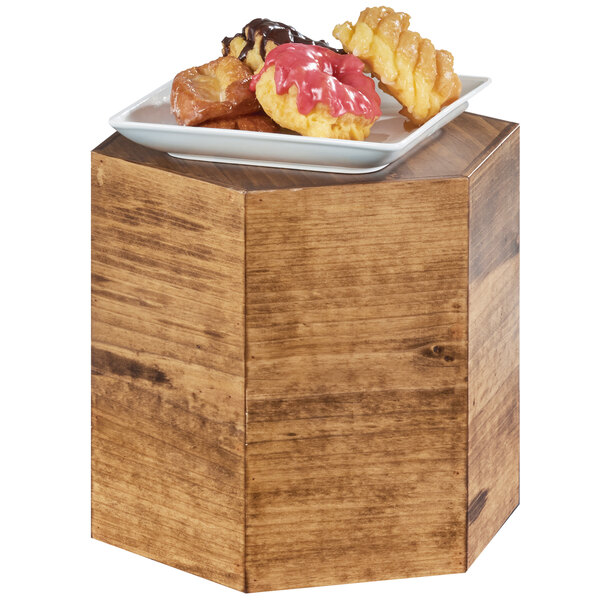 A Cal-Mil Madera oak wood hexagon riser with a plate of pastries on top.
